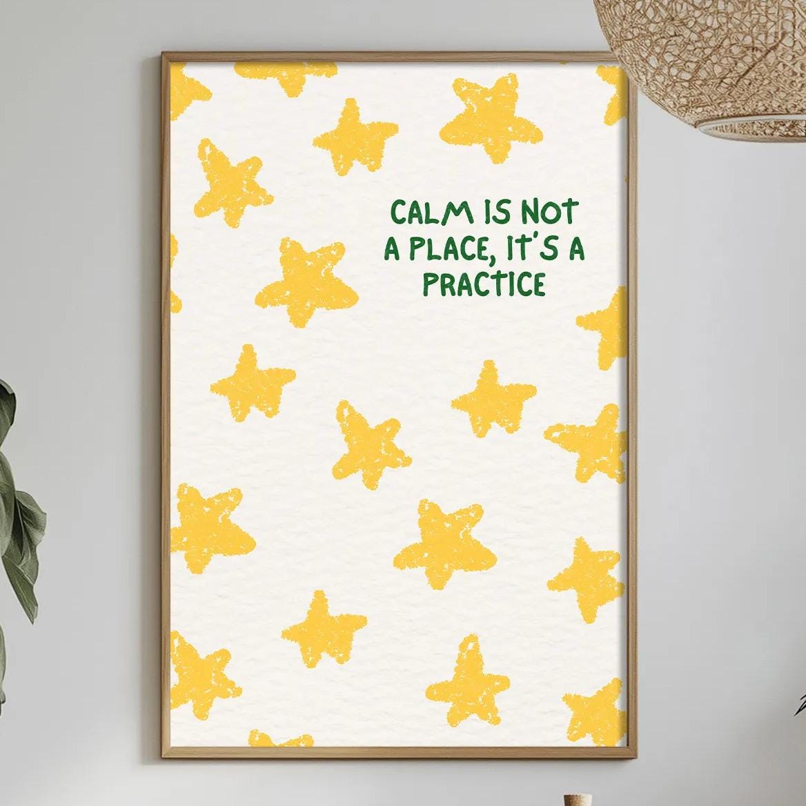 a dining table with a white tablecloth, a bowl of fruit, a bottle, and a vase with flowers. Above the table, there is a framed poster with a yellow star pattern and the text "Calm is not a place, it's a practice" displayed on it.