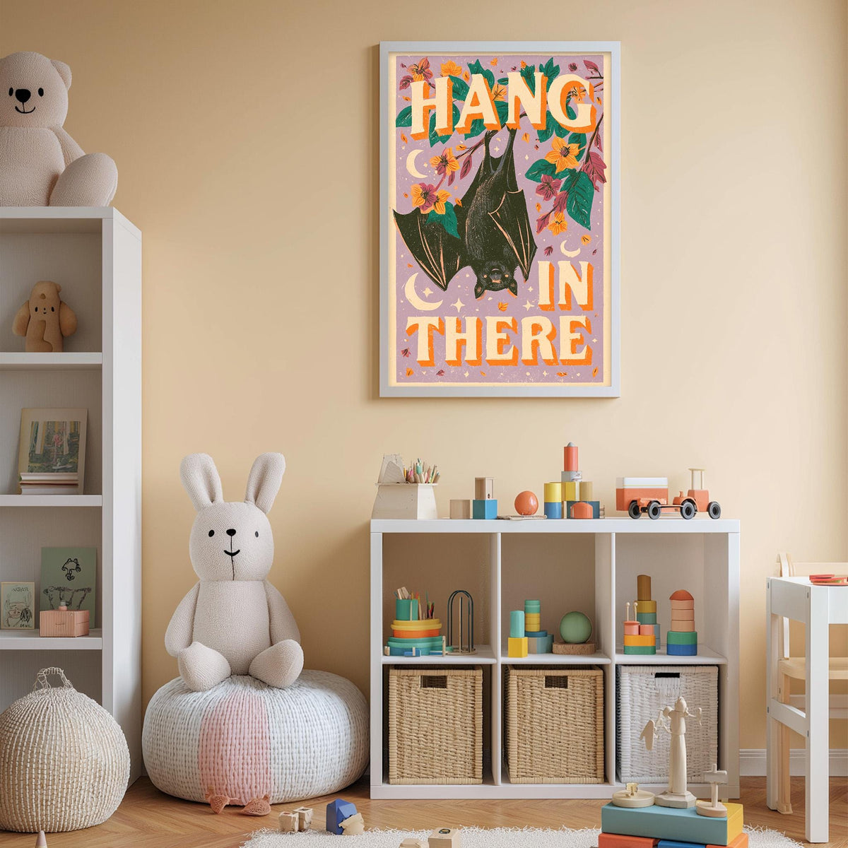 A child's bedroom with a white bookshelf, a stuffed rabbit, and a colorful poster on the wall. The poster features a bat and the text "HANG IN THERE".