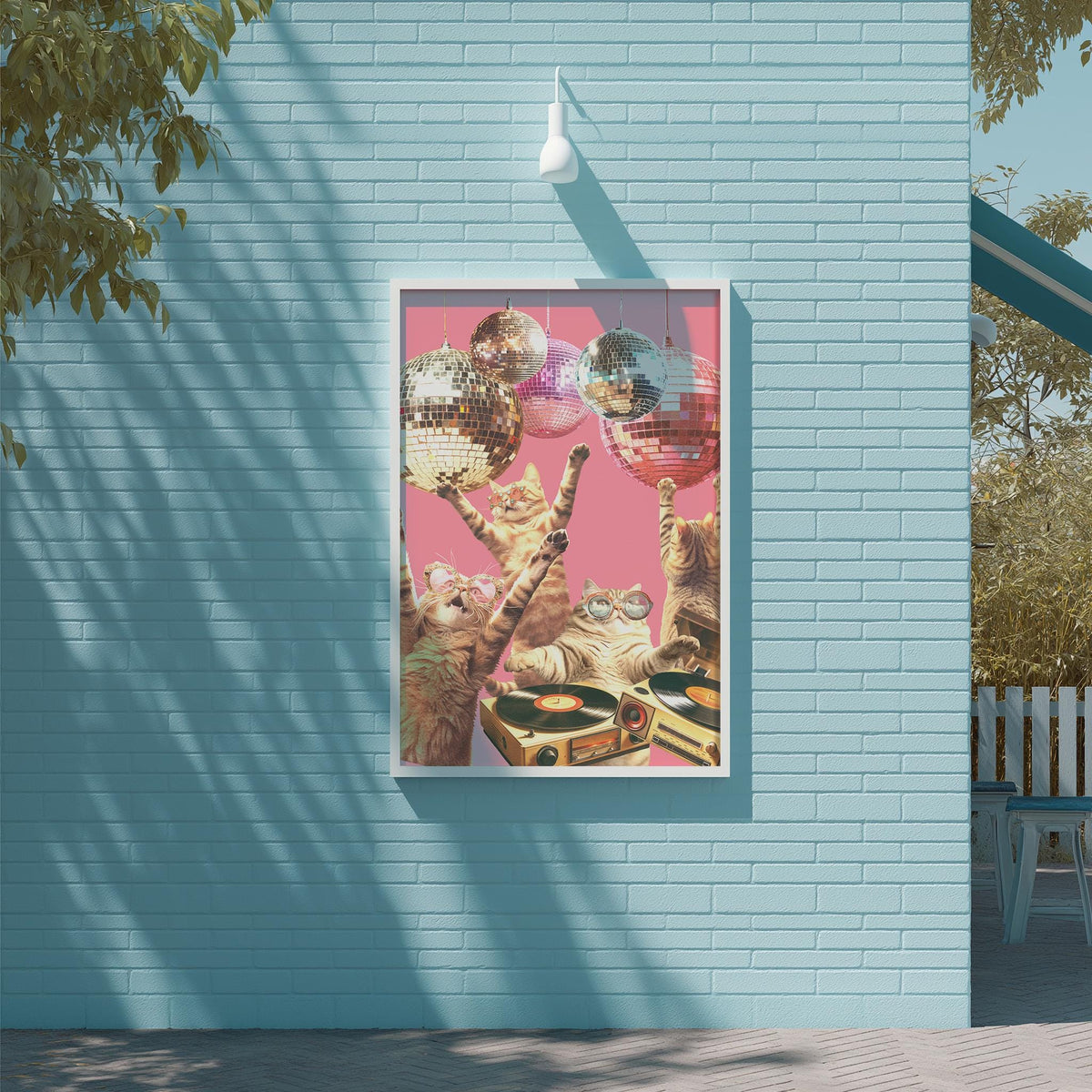 A framed collage of cats playing with disco balls on a wall, with a pink background and a white light fixture above.