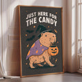 A framed poster with a cartoon image of a beaver dressed as a witch, holding a carved pumpkin, and the text "Just here for the candy" against a dark background with bats and stars.