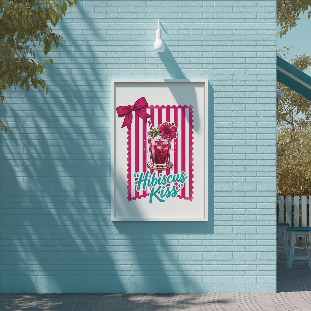 A framed poster with a pink and white striped border, featuring a glass with a flower and the text "Hibiscus Kiss" is displayed on a blue wall.