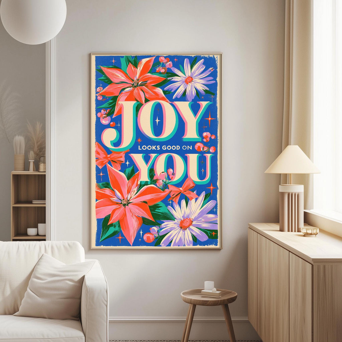 a vibrant poster with a floral design and the text "JOY LOOKS GOOD ON YOU" displayed on a wall in a living room setting.