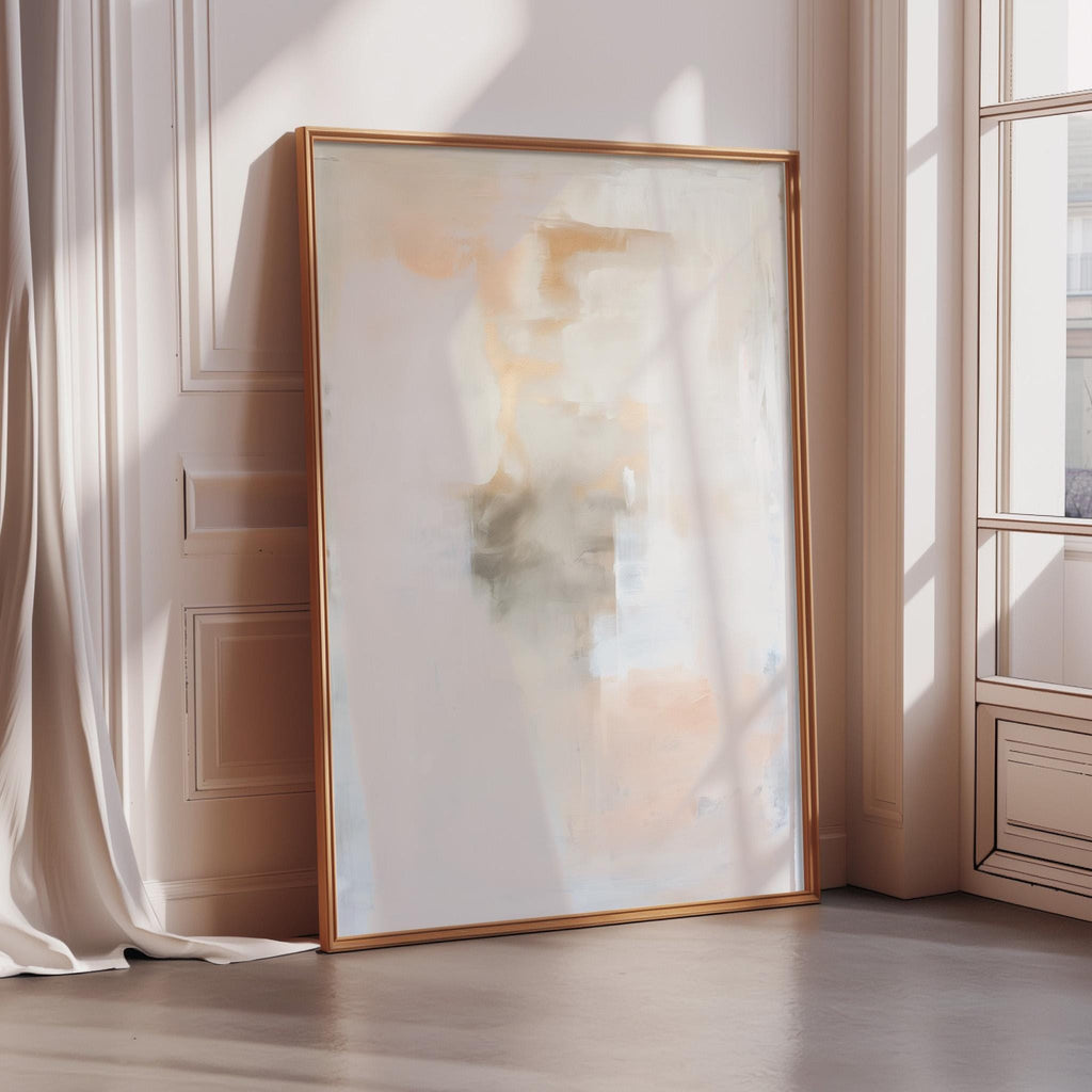 a large, abstract painting with a white background and a warm, orange and yellow color palette. The painting is displayed on a wall, leaning against a window, and is framed in a gold frame.