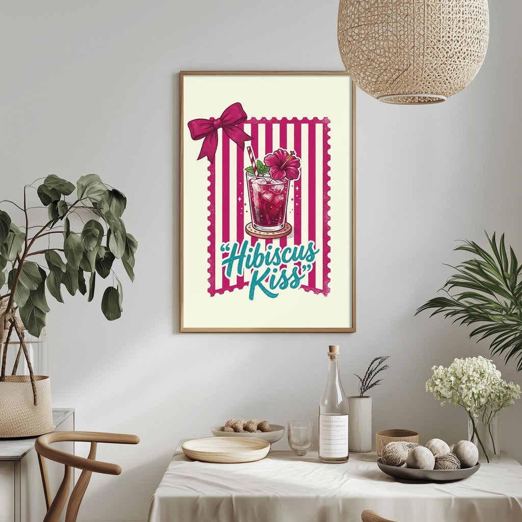 a framed poster with a pink and white striped border, a glass with a flower, and the text "Hibiscus Kiss" written on it. The poster is hanging on a wall above a dining table with various items on it, including a bottle, a bowl, and a vase.
