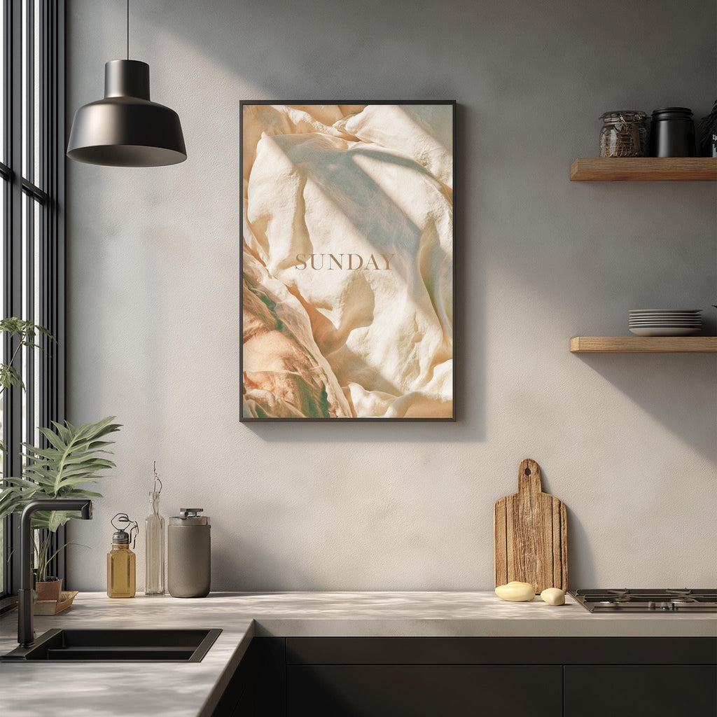 a kitchen counter with various kitchen items, including a cutting board, a bottle, and a plant. Above the counter, there is a framed poster with the word "SUNDAY" written on it.