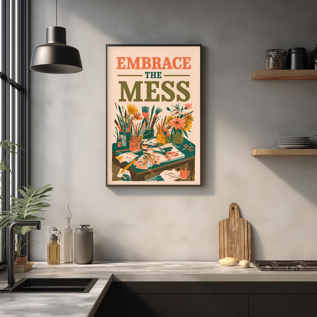 a kitchen counter with various items such as a cutting board, a soap dispenser, and a plant. Above the counter, there is a framed poster with the text "Embrace the mess" and an illustration of a cluttered workspace.