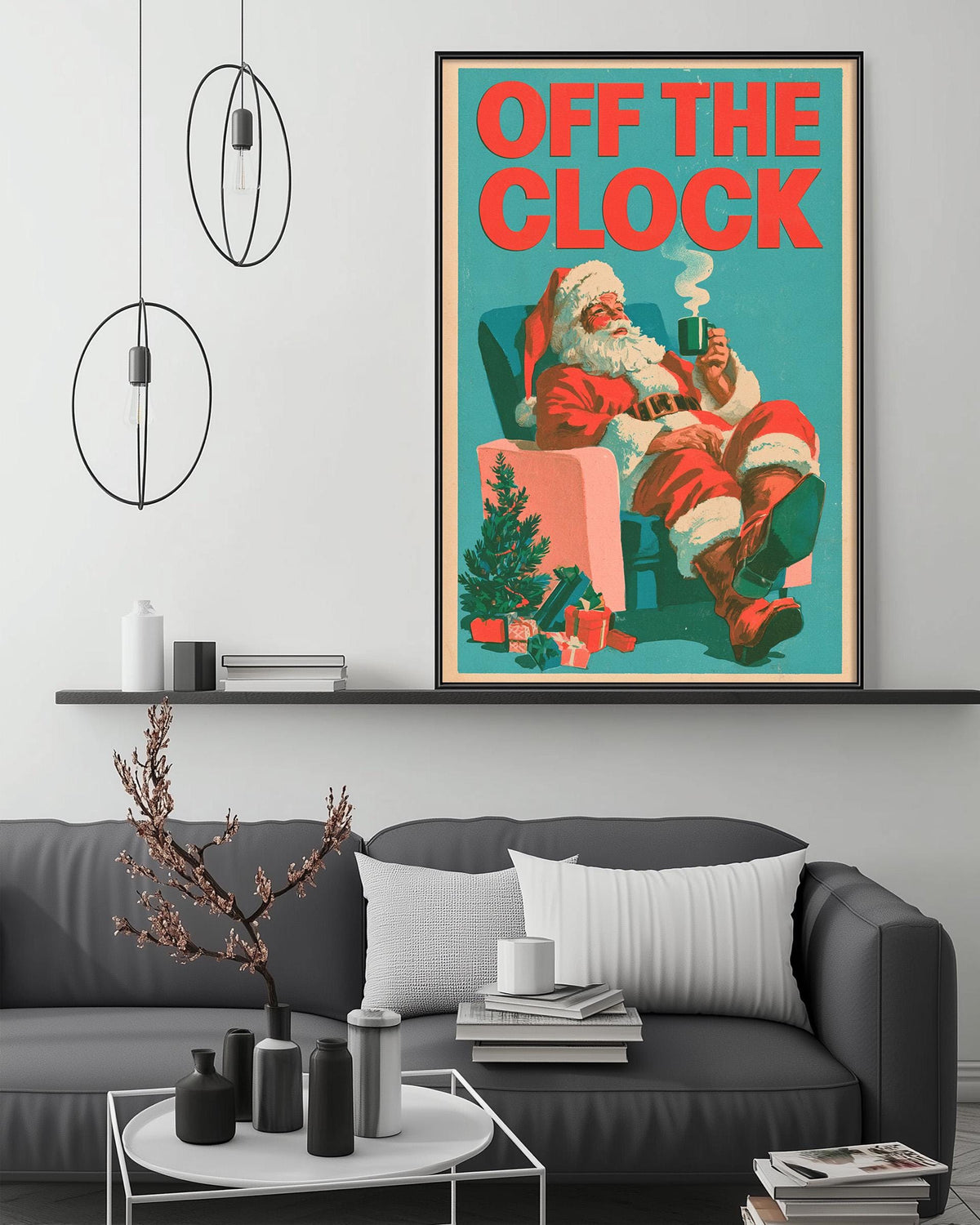 a cozy living room with a large framed poster of Santa Claus sitting in a chair, holding a cup of coffee, and surrounded by holiday decorations. The poster is hanging on the wall above a gray couch, which has a coffee table in front of it. The room also includes a bookshelf, a potted plant, and some decorative items on the coffee table.
