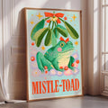 a poster with a green frog sitting under a mistletoe.