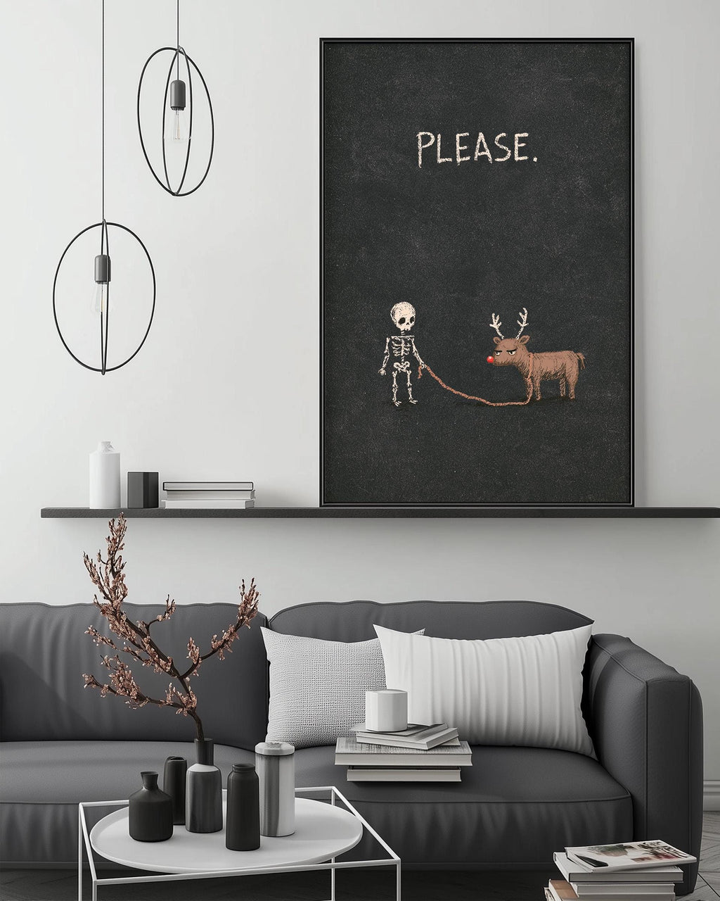 a living room with a gray sofa, a coffee table, and a large black framed poster with a skeleton and reindeer on it. The poster has the word "PLEASE" written on it.