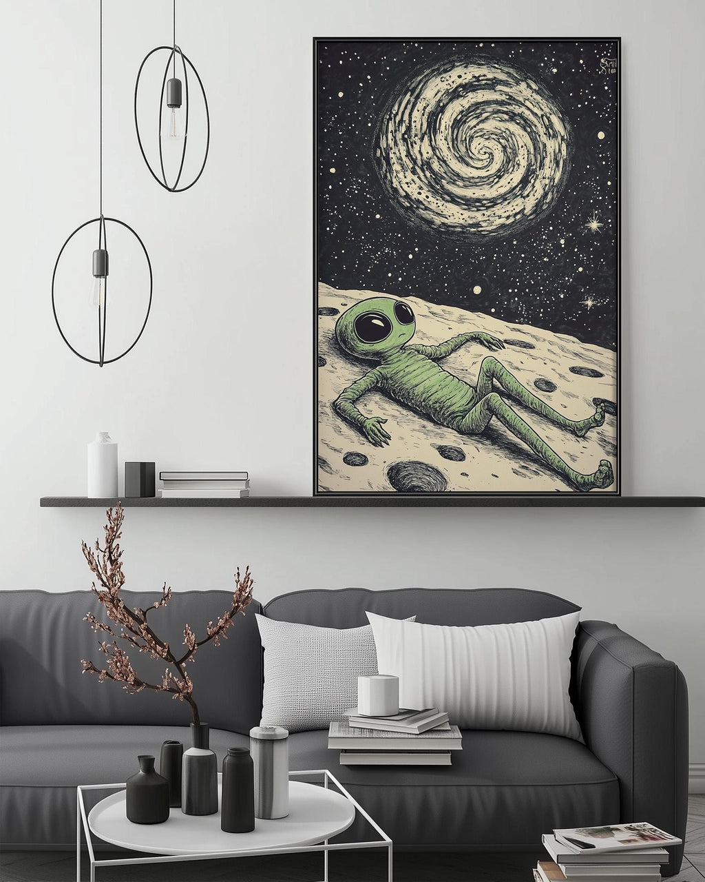 a large framed artwork depicting an alien lying on a surface, with a spiral galaxy in the background. The artwork is displayed above a gray couch in a living room setting, with a coffee table and various decorative items in the foreground.