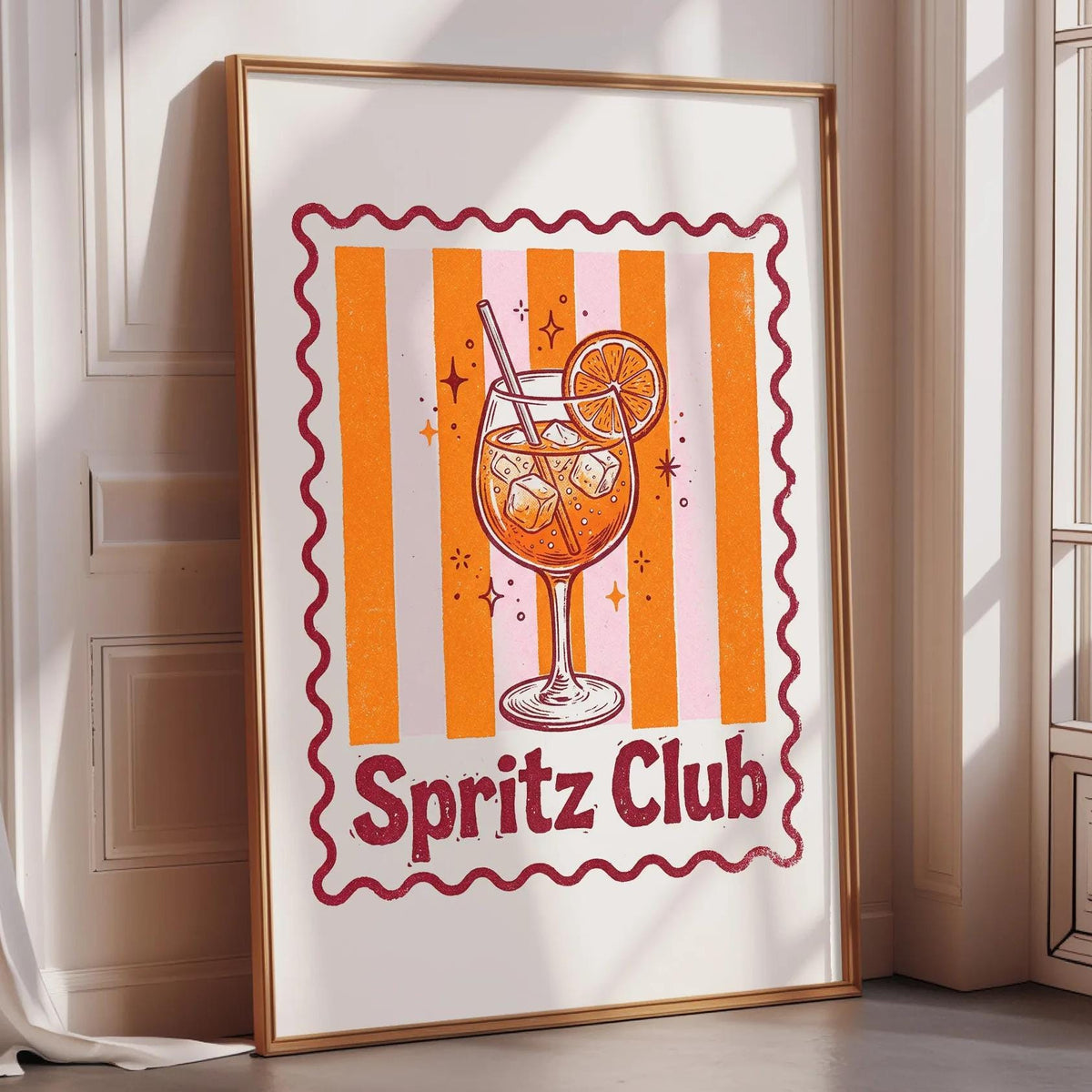 A framed poster of a cocktail glass with a slice of orange, surrounded by orange and white stripes, and the text "Spritz Club" is displayed on a wall.