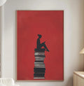 a cozy living room with a large red poster featuring a silhouette of a person sitting on a stack of books, which is the focal point of the room.