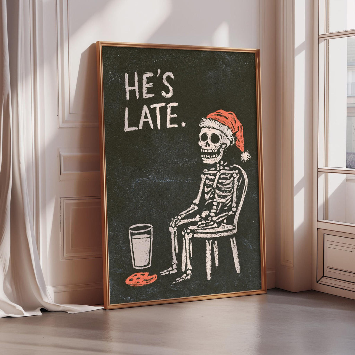 A framed illustration of a skeleton wearing a Santa hat and sitting in a chair, with the text "HE'S LATE."