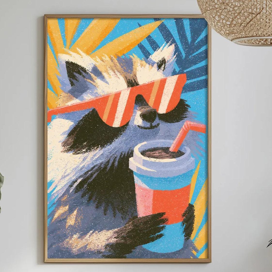a vibrant and colorful painting of a raccoon wearing sunglasses and holding a drink, hanging on a wall above a dining table with various decorative items and plants.