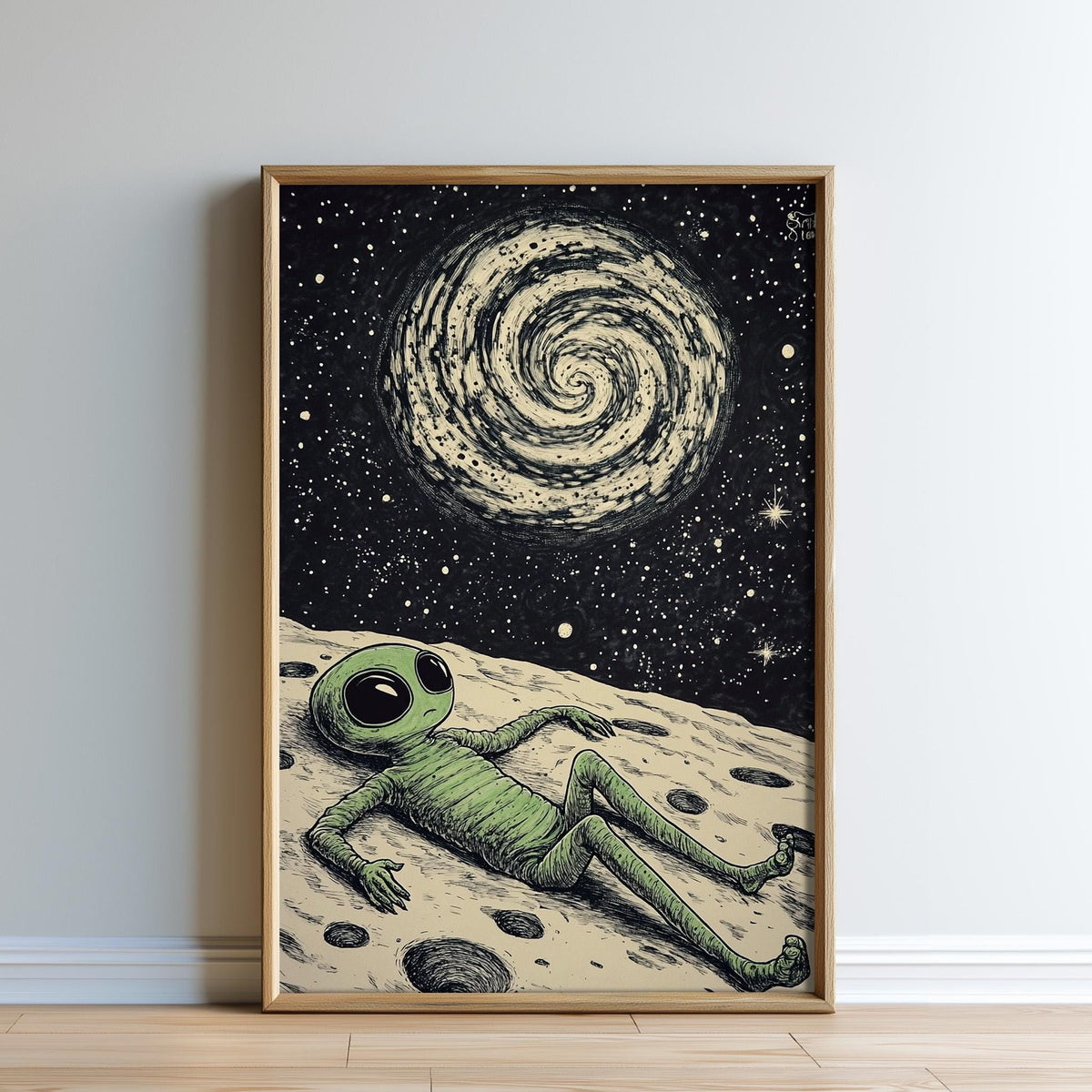 The image is a framed illustration depicting an alien lying on a rocky surface, gazing up at a spiral galaxy in the night sky.