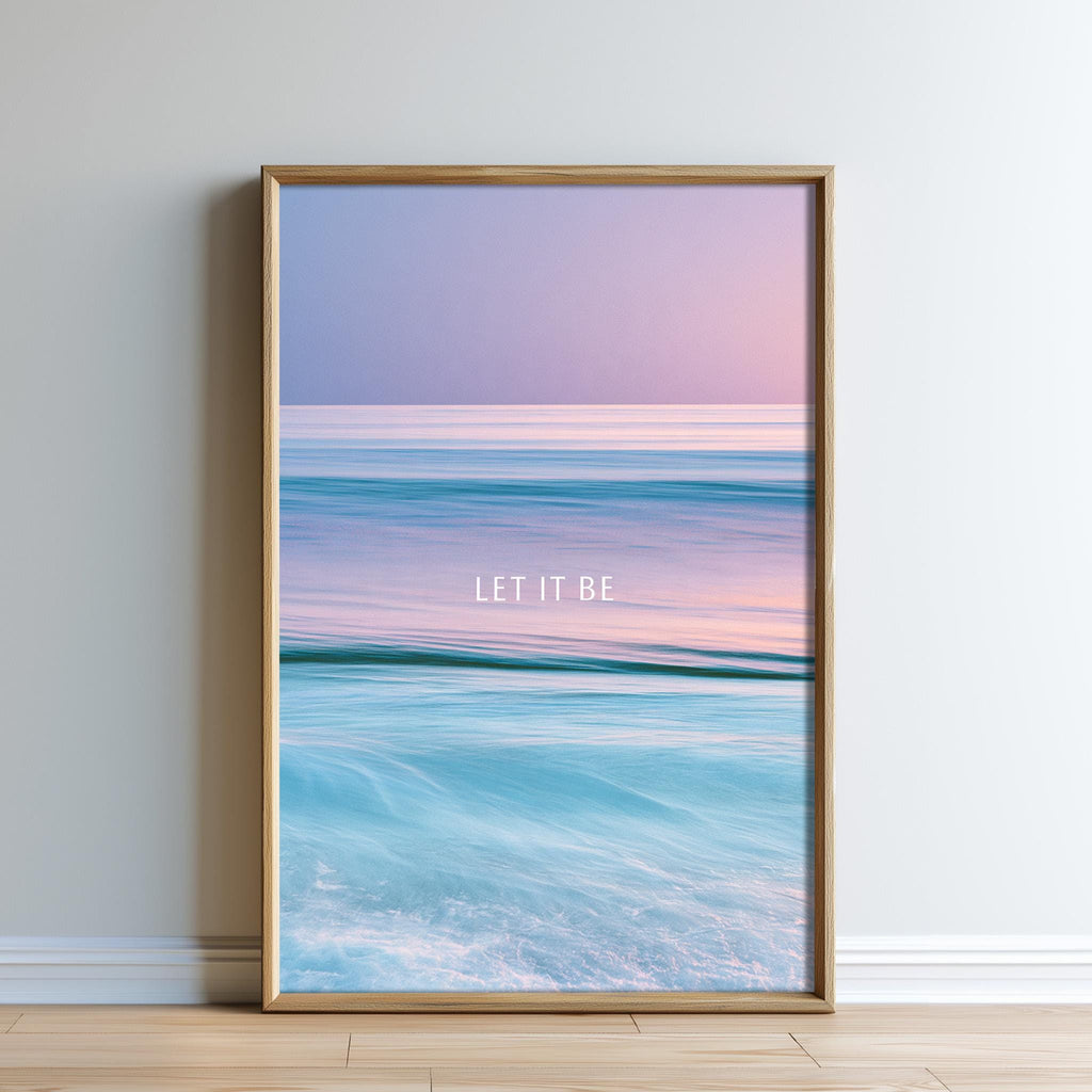 A framed poster with a serene ocean scene, featuring a gradient of colors from blue to pink, and the text "LET IT BE" overlaid on the image.