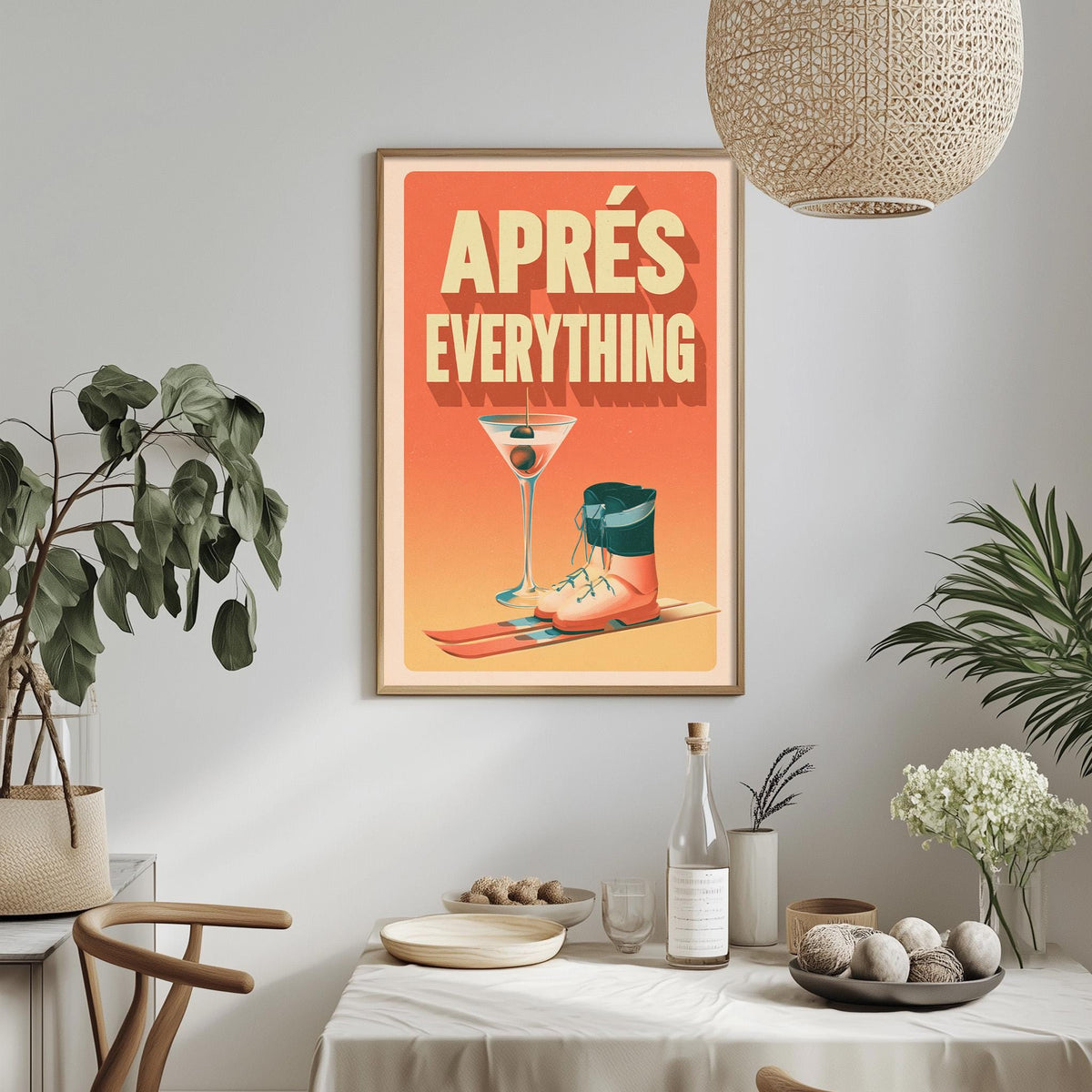 a framed poster with the text "APRES EVERYTHING" hanging on a wall above a dining table with various items on it, including a plant, a bottle, and a bowl.
