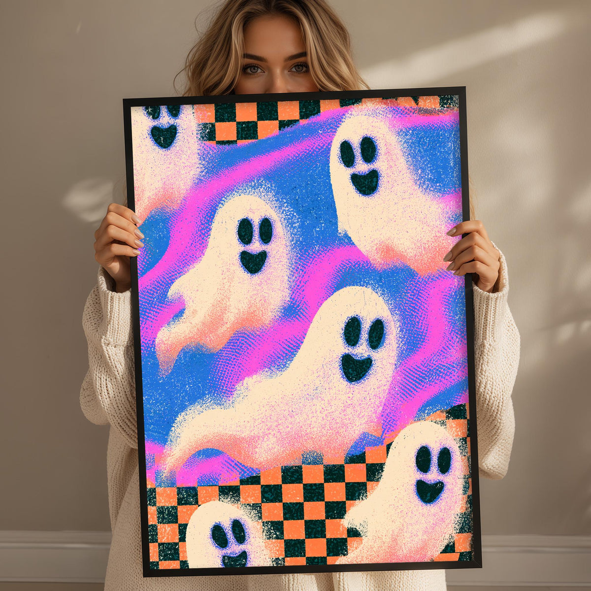 A woman is holding up a framed poster with a vibrant, colorful design featuring multiple ghost-like figures.