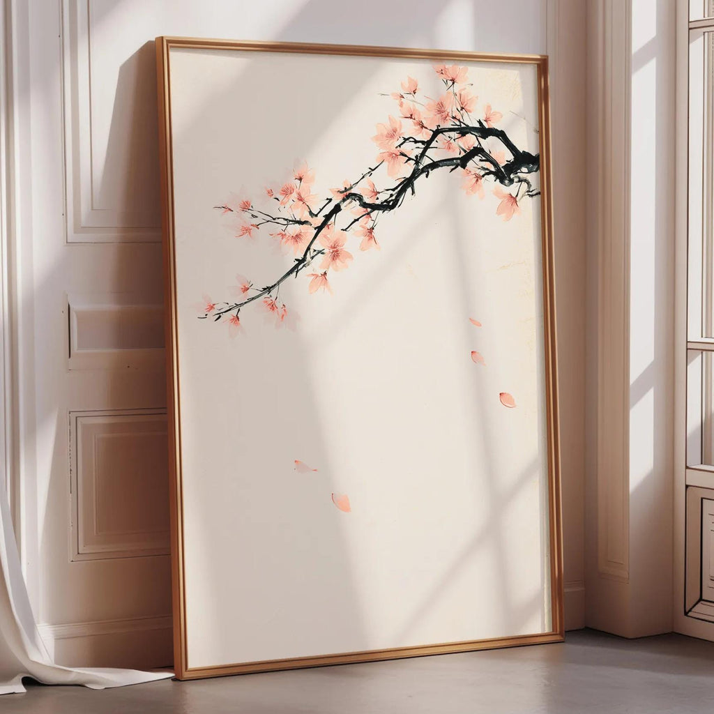 A large framed print depicting a branch with pink flowers is leaning against a white wall in a room with a window.