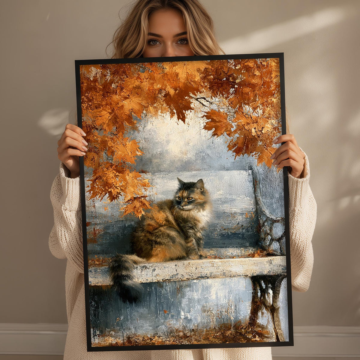A woman holds up a framed painting depicting a cat sitting on a bench surrounded by autumn leaves.