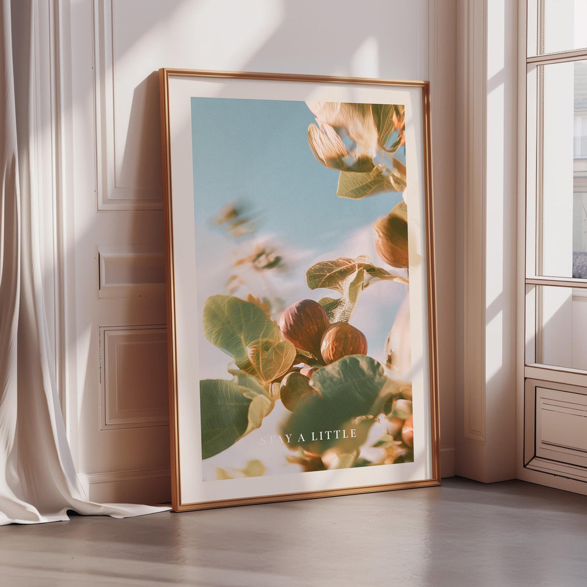 a large framed poster with a vibrant, nature-inspired image of leaves and flowers, displayed on a wall in a room with sunlight streaming in from a window.
