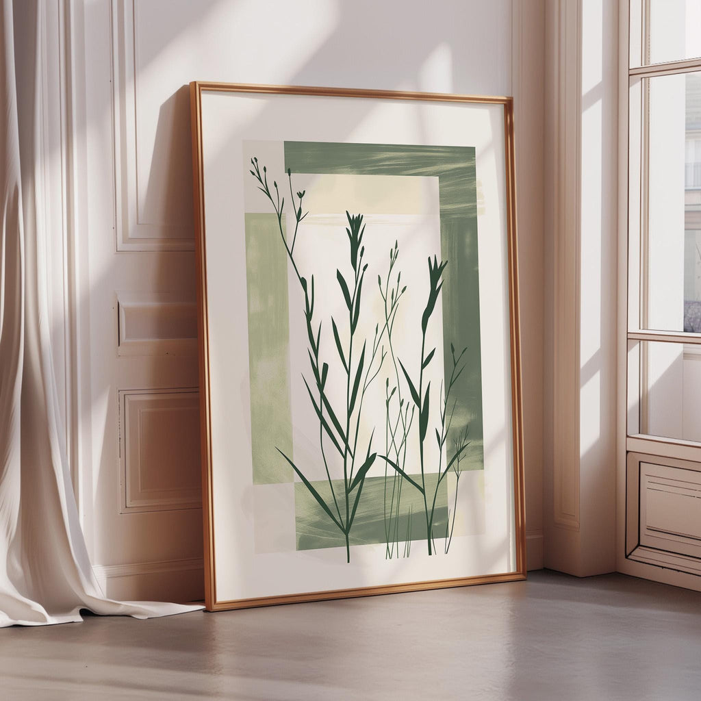 a large framed artwork depicting a green plant with long leaves, placed on a wooden floor next to a window.