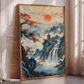 A large framed painting depicting a serene landscape with a waterfall, mountains, and a pagoda in the background, set against a vibrant sky with a large orange sun.
