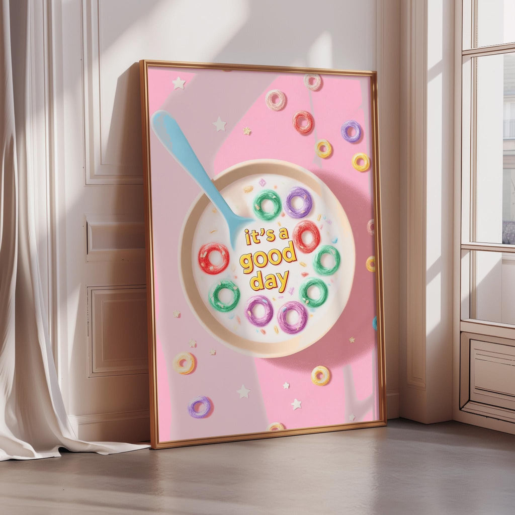A framed poster with a pink background and a bowl of colorful donuts. The text on the poster says "It's a good day".