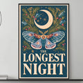 a large framed poster with a butterfly and a crescent moon on it, hanging on a wall above a gray couch with a coffee table in front of it.