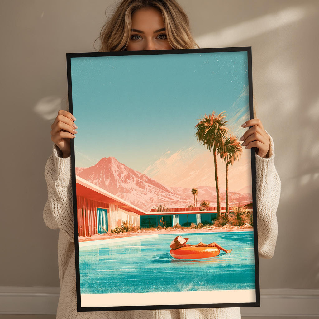 A woman holds up a framed print depicting a serene scene of a person relaxing in a pool, surrounded by palm trees and mountains.