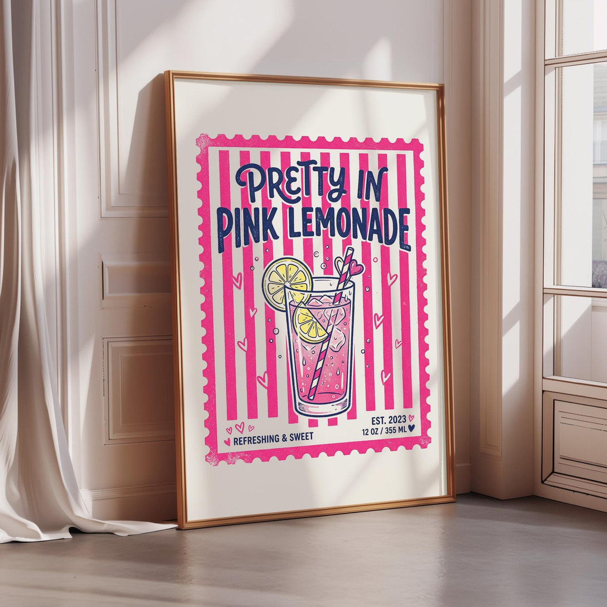 A framed poster advertising "Pretty in Pink Lemonade" with a pink and yellow color scheme and a glass of lemonade with a straw.