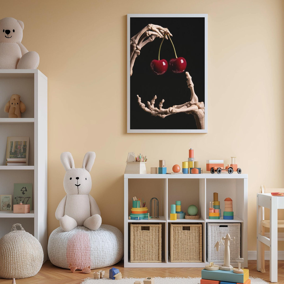 A child's bedroom with a white bookshelf, a stuffed rabbit, a toy skeleton holding cherries, and a framed artwork depicting a skeleton hand holding cherries.