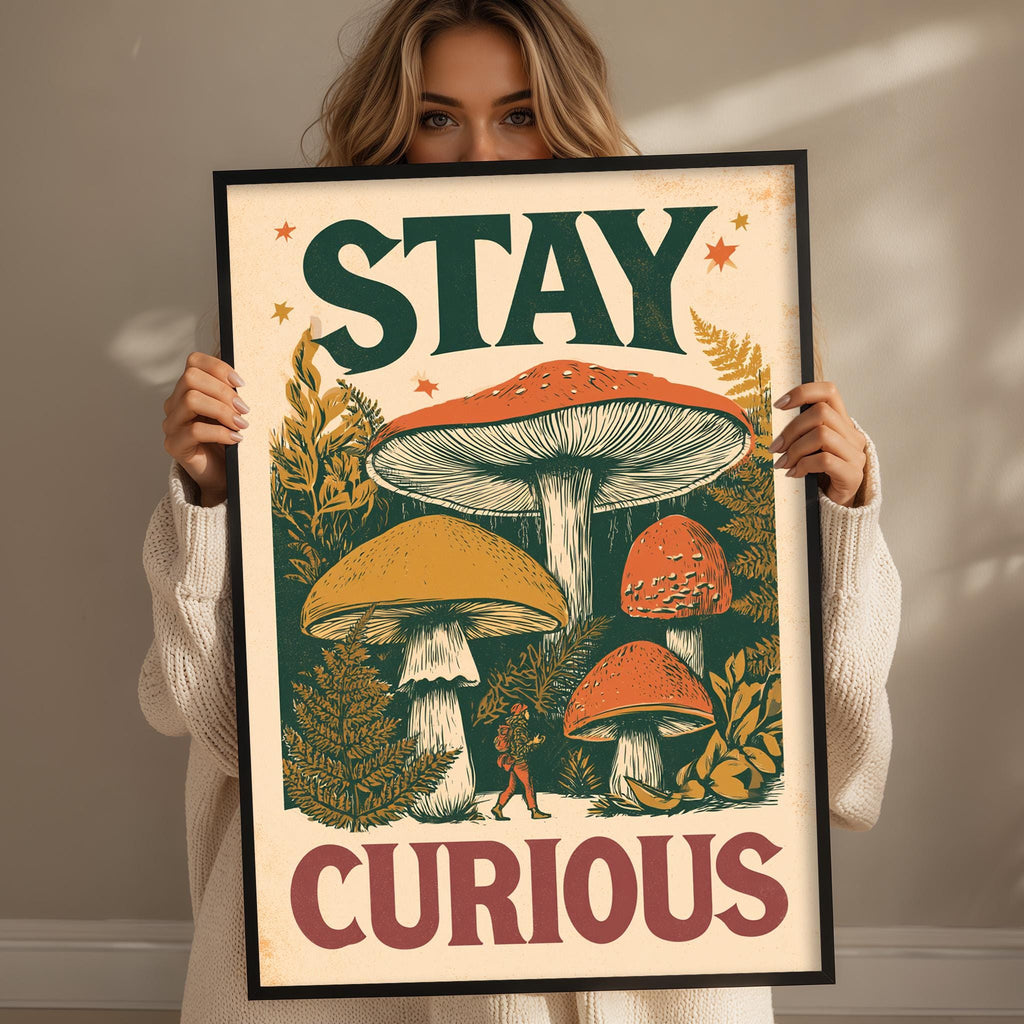 A woman is holding up a framed poster with a mushroom illustration and the text "STAY CURIOUS" on it.