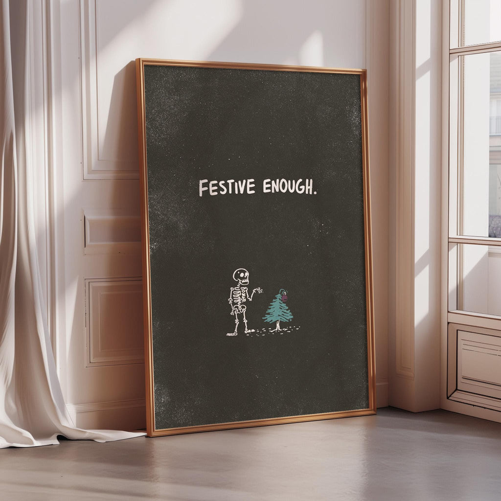 a chalkboard with the text "FESTIVE ENOUGH" written on it, along with a skeleton and a Christmas tree drawn on it.
