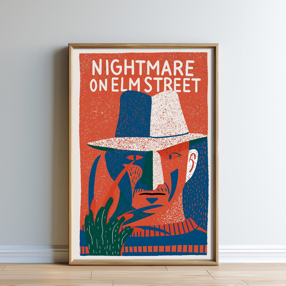 The image is a framed poster featuring an illustration of a man's face wearing a hat, with the text "NIGHTMARE ON ELM STREET" prominently displayed.
