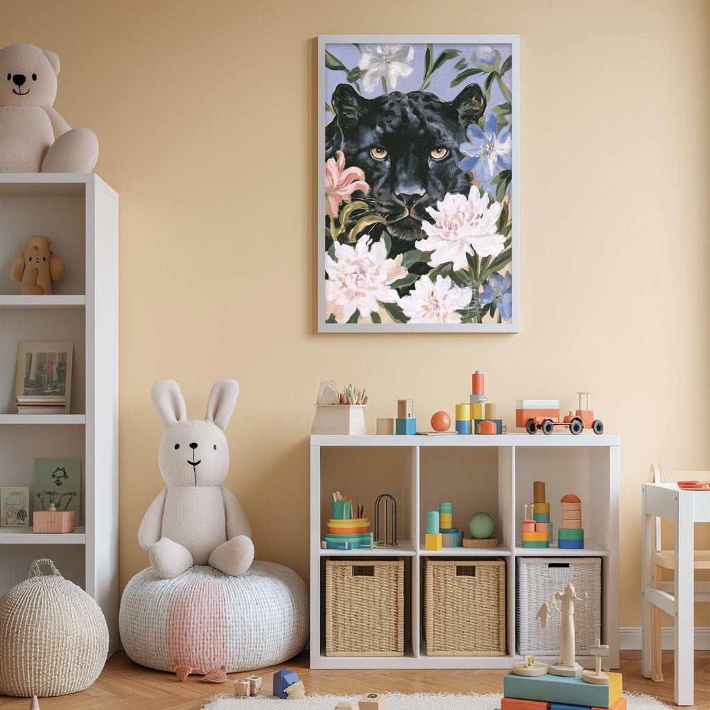A child's bedroom with a large framed painting of a black panther surrounded by flowers on the wall, a white bookshelf filled with toys, and a white bean bag chair.