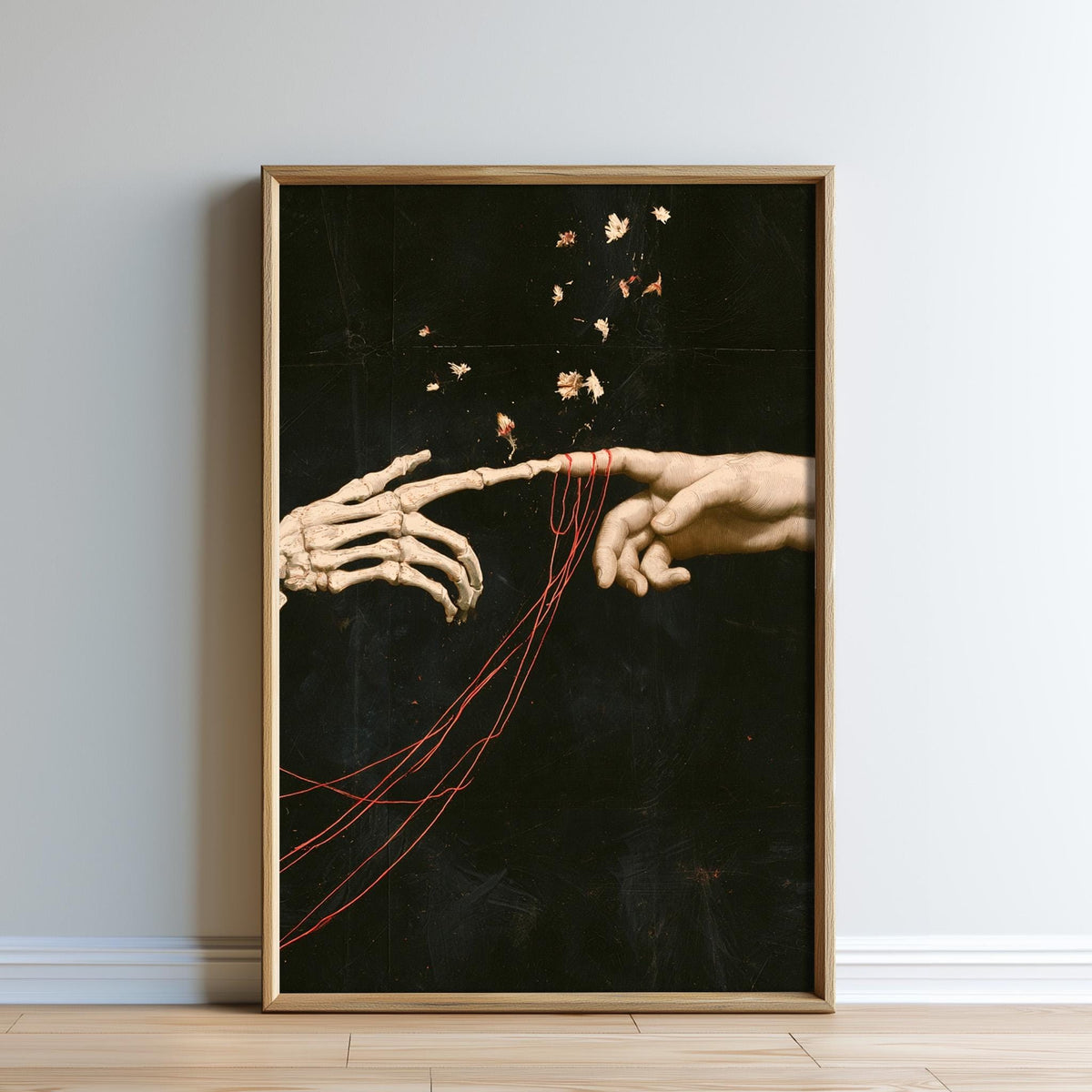 A framed artwork depicting two skeletal hands reaching towards each other, with red strings connecting them, against a dark background with scattered red strings.