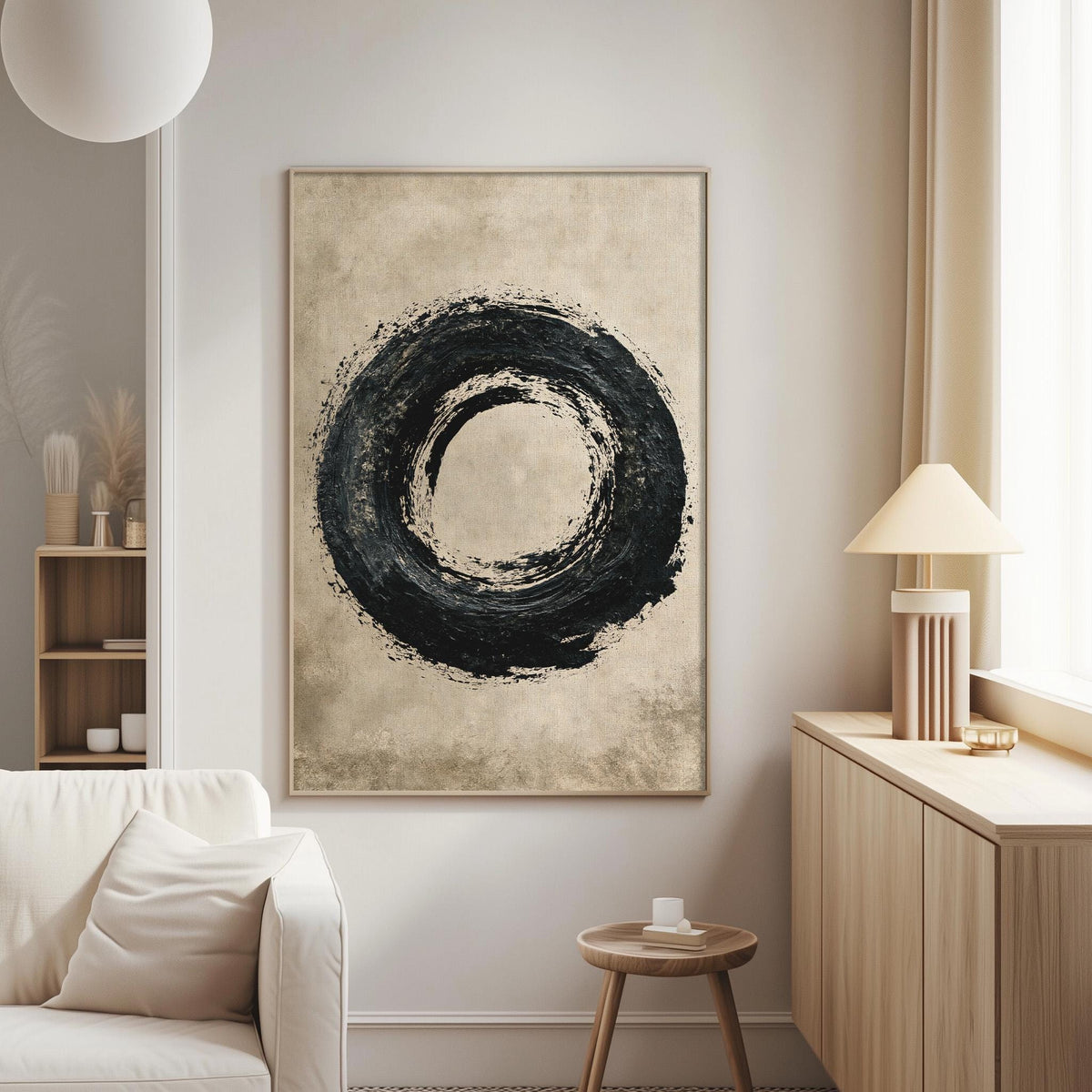 a modern living room with a large abstract painting featuring a black circle on a beige background hanging on the wall. The room is furnished with a white sofa, a wooden side table, and a lamp on a wooden cabinet.