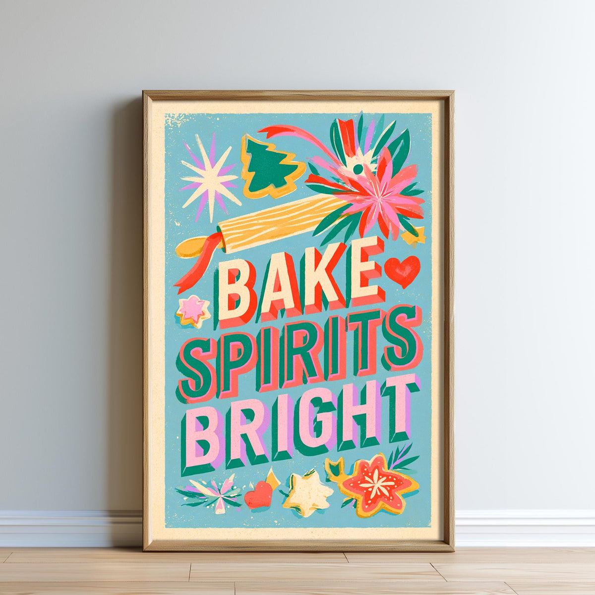 The image is a framed poster with a vibrant design featuring the text "Bake, Spirits, Bright" surrounded by various decorative elements such as flowers, stars, and a rolling pin.