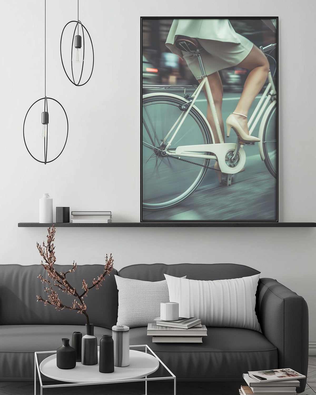 a modern living room with a gray sofa, a coffee table, and a large framed photograph of a woman riding a bicycle.