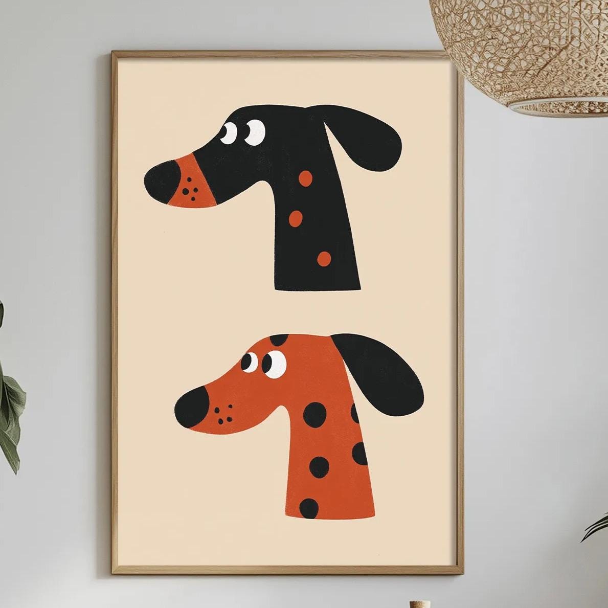 a dining table with a white tablecloth, a bowl of fruit, a bottle, and a vase with flowers. Above the table, there is a framed picture of two cartoon-style dog heads, one black and one orange, hanging on the wall.