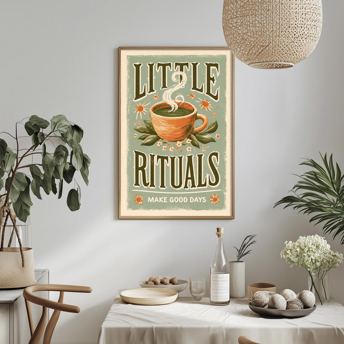 a framed poster with the text "LITTLE RITUALS MAKE GOOD DAYS" hanging on a wall above a dining table with various items on it.