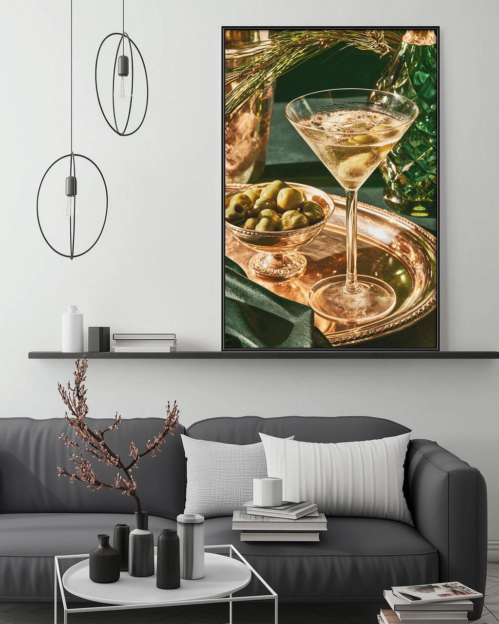 a large framed picture of a martini glass filled with a drink, placed above a gray couch with a coffee table in front of it.