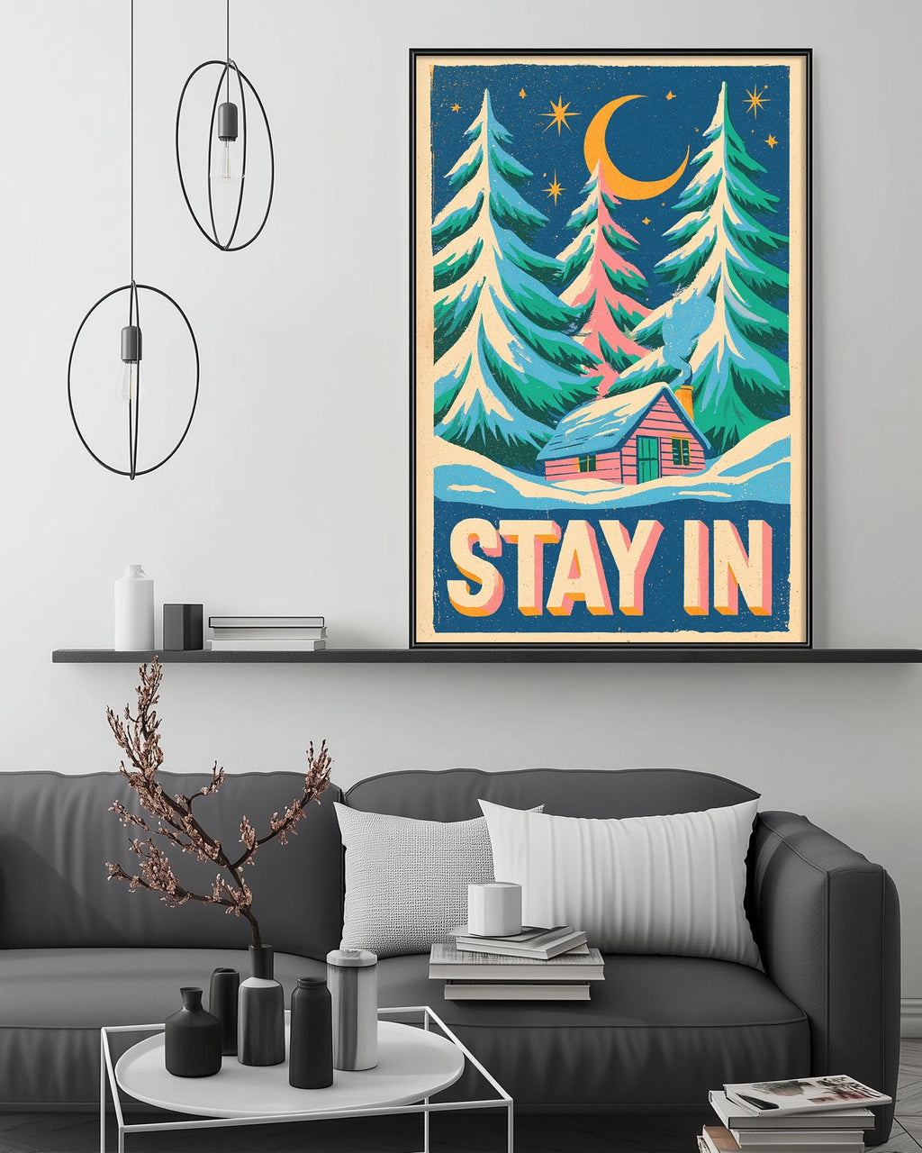 a cozy living room with a gray couch, a coffee table, and a framed poster of a snowy forest scene with a cabin. The poster has the text "STAY IN" written on it.