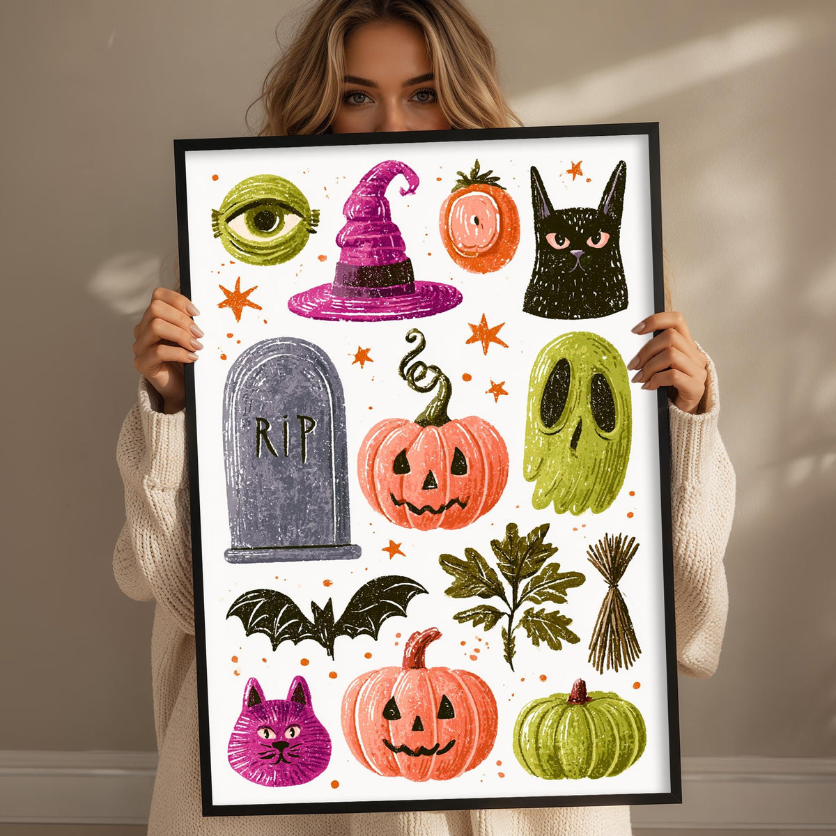 A woman is holding up a framed collage of Halloween-themed illustrations, including a witch's hat, a pumpkin, a ghost, a skeleton, a bat, a cat, and a pumpkin.