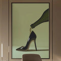 a modern and stylish office space with a large framed artwork of a high-heeled shoe on the wall, a wooden desk with a chair, and built-in bookshelves.