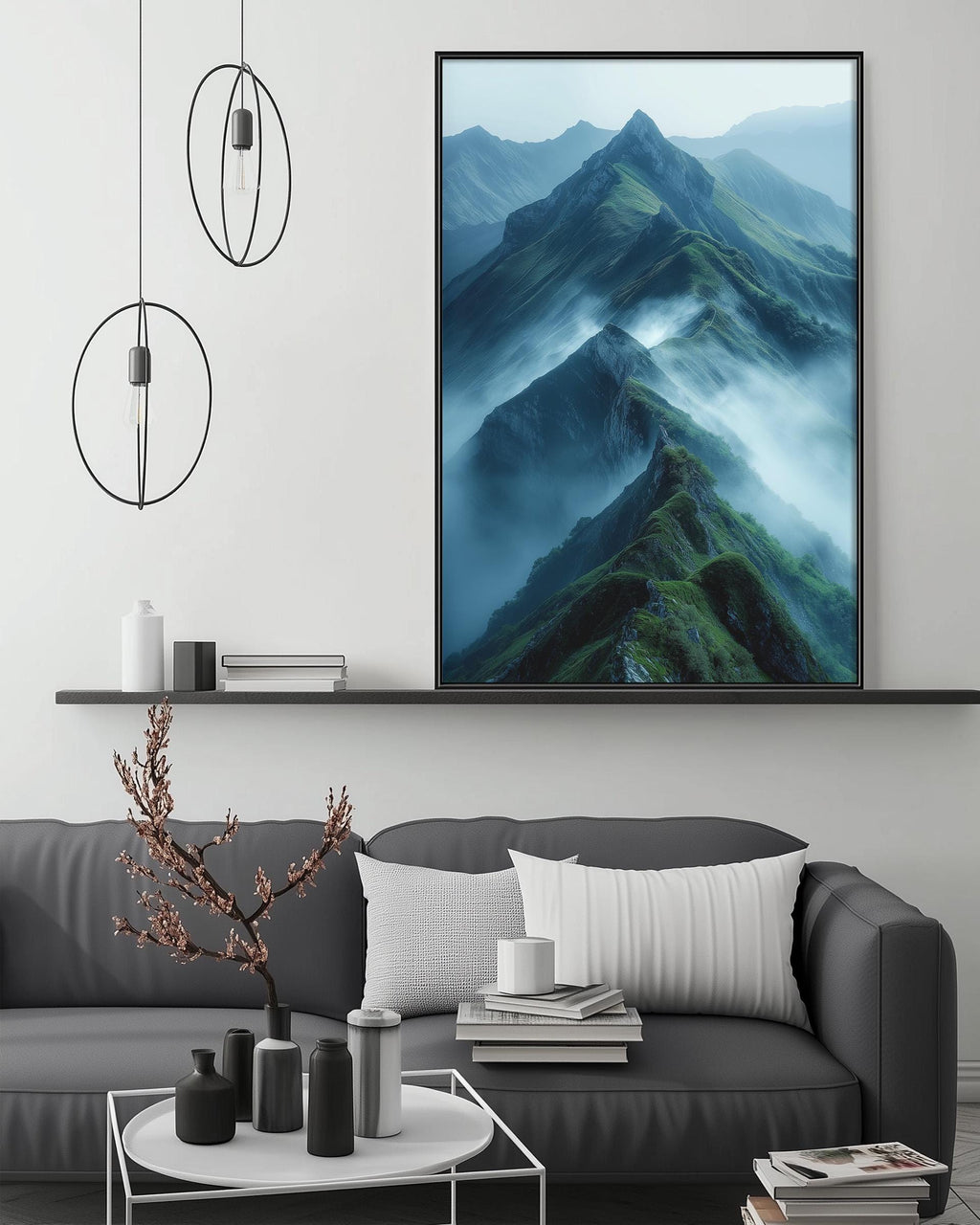 a large framed picture of a mountain landscape with a misty, green and blue background, hanging on a wall above a gray couch with a coffee table in front of it.