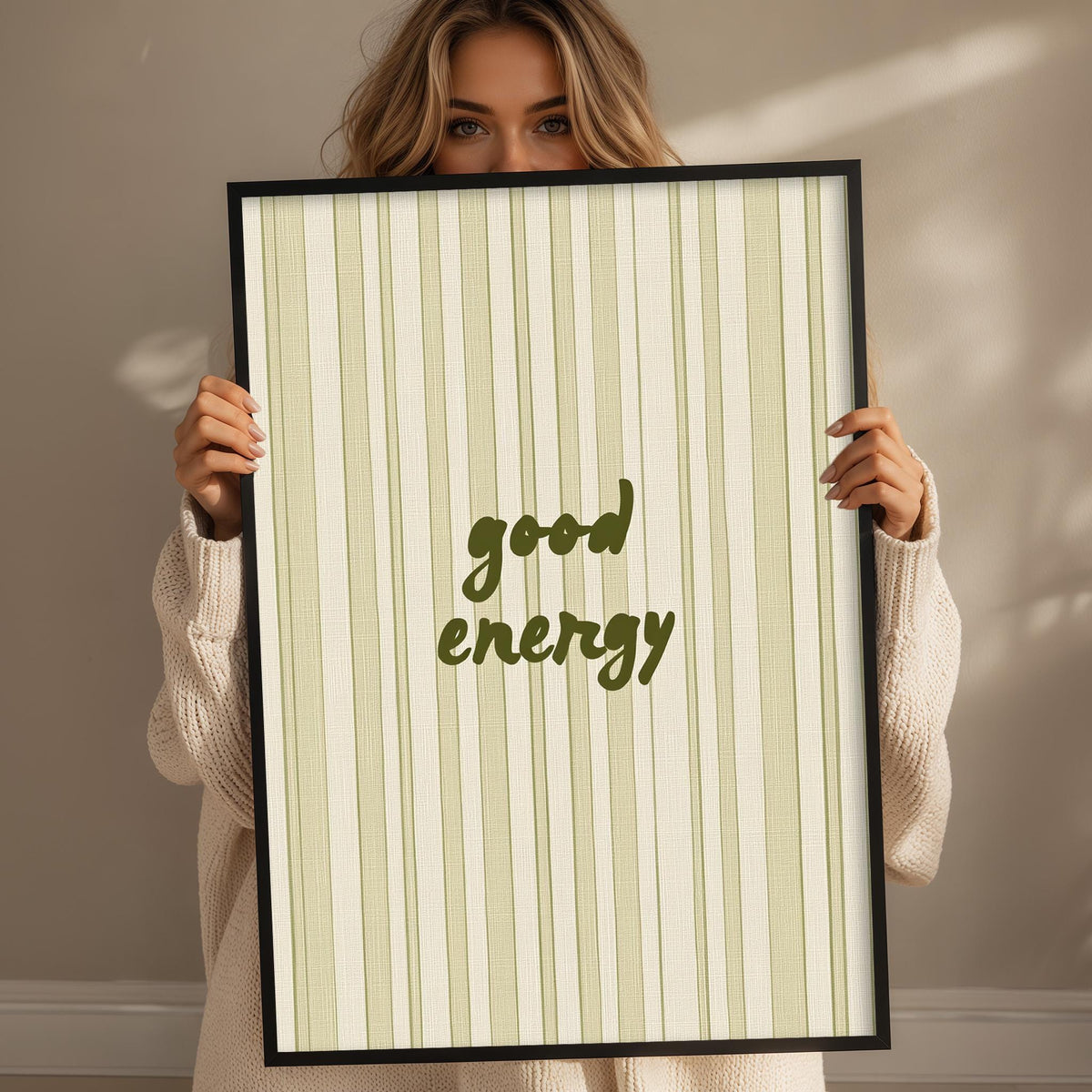 A woman holding a framed poster with the text "good energy" on it.