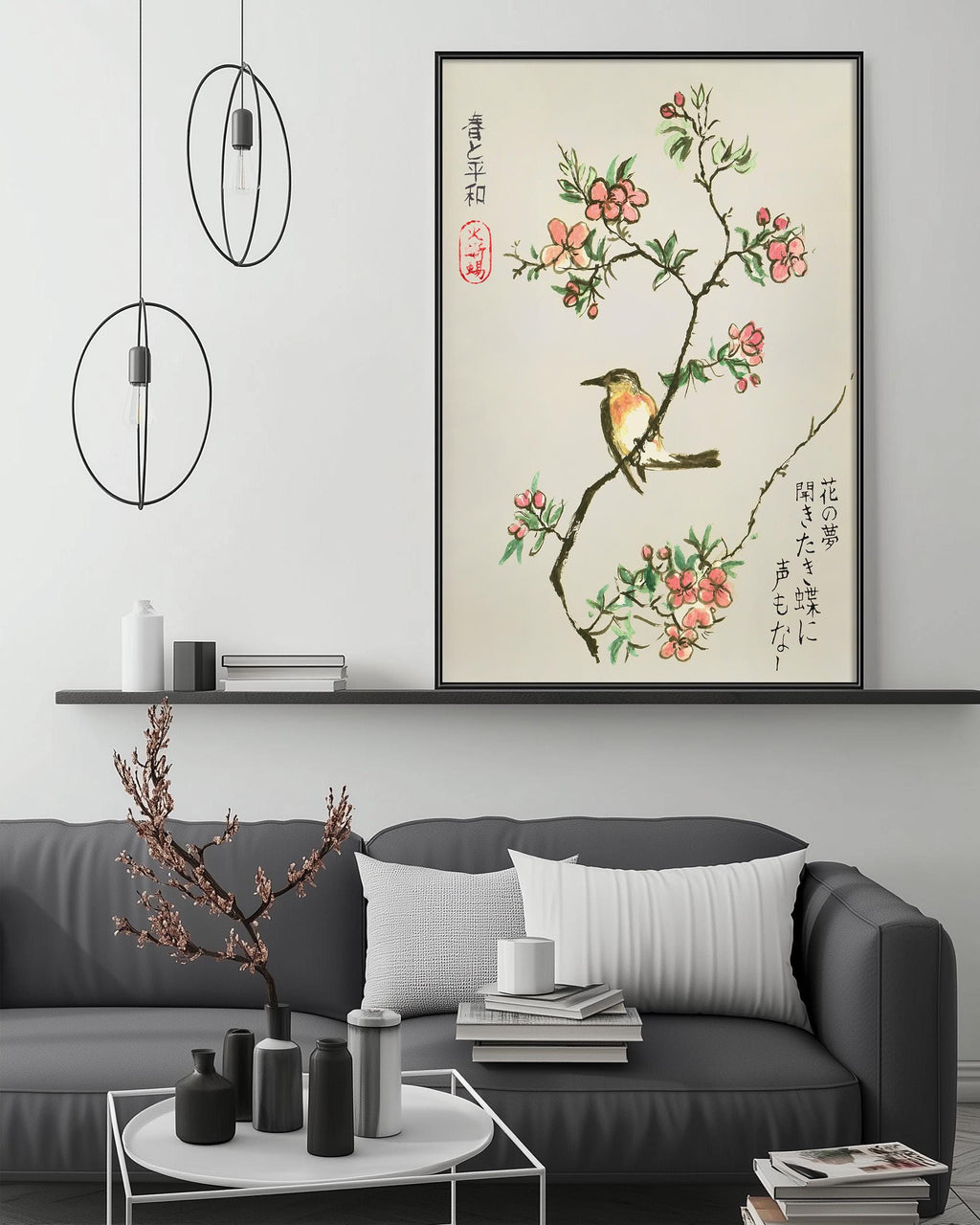 a living room with a gray sofa, a coffee table, and a framed artwork of a bird perched on a branch with flowers. The artwork is hung on the wall above the sofa, creating a focal point in the room.