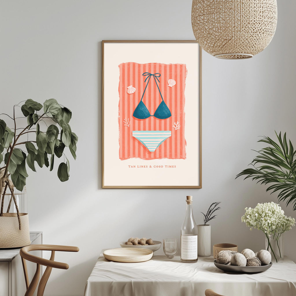 a framed illustration of a bikini and a striped towel, hanging on a wall above a dining table with various decorative items and plants.
